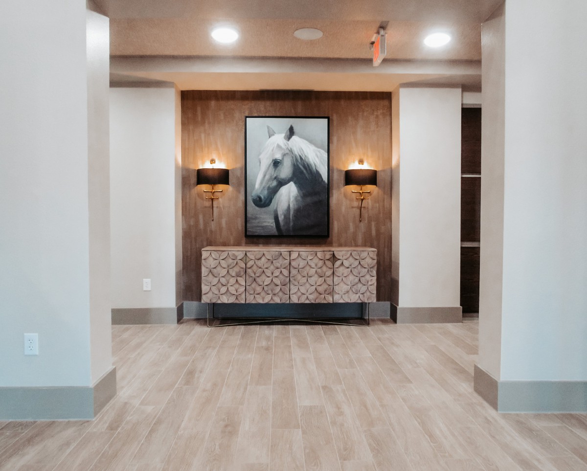 A modern hallway featuring a horse painting, stylish lamps, and a wooden floor.