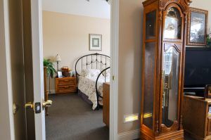 A cozy bedroom with a wrought iron bed, wooden nightstand, and a grandfather clock.