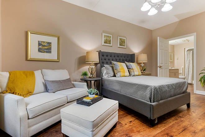 A cozy bedroom featuring a stylish bed with decorative pillows, a comfortable sofa, and elegant lighting.