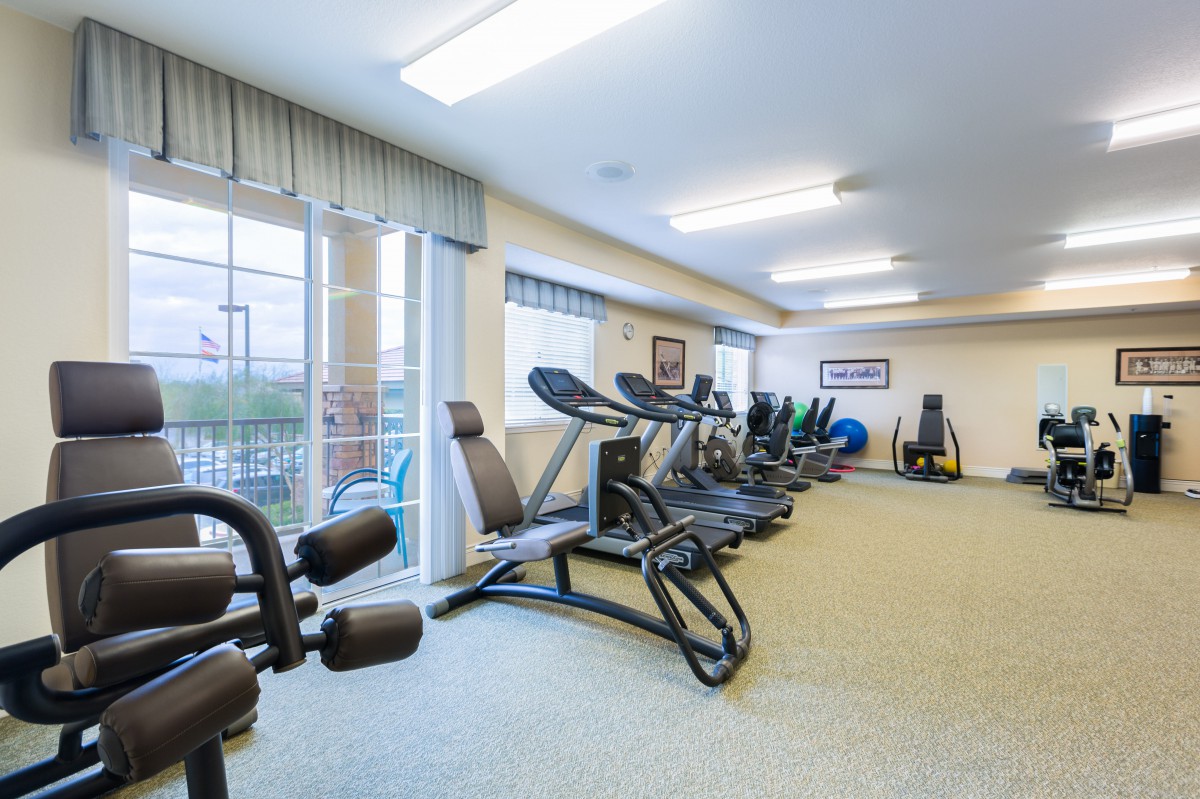 A well-equipped gym with multiple treadmills and elliptical machines lined up in a spacious, well-lit room.