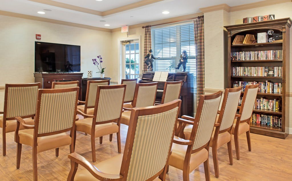 A modern conference room with neatly arranged chairs and a television.