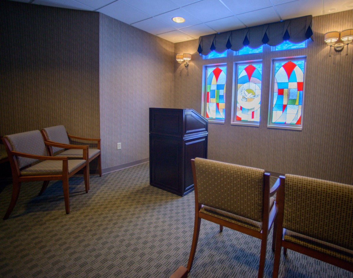 A serene chapel interior with stained glass windows and arranged seating.