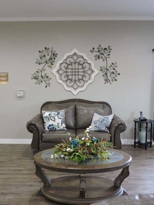A cozy living room featuring a comfortable sofa, decorative wall art, and a glass coffee table with floral centerpiece.