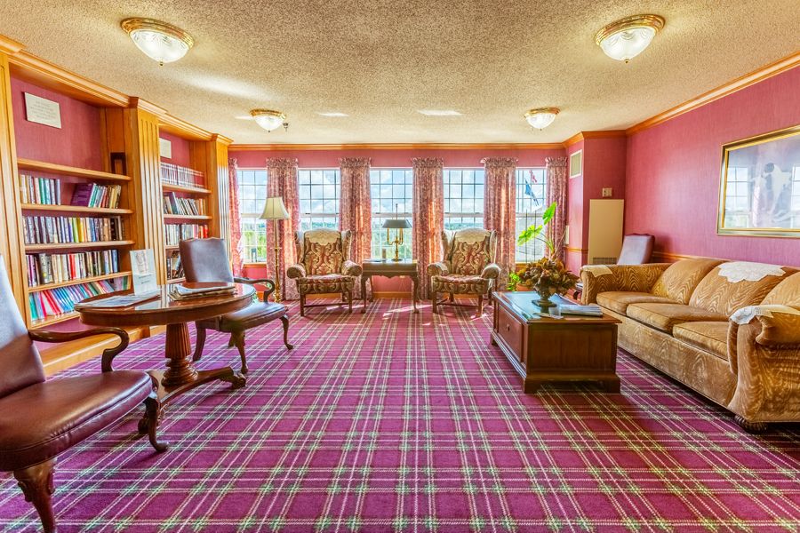 A classic-style living room with red plaid carpet, featuring elegant furniture and large windows.