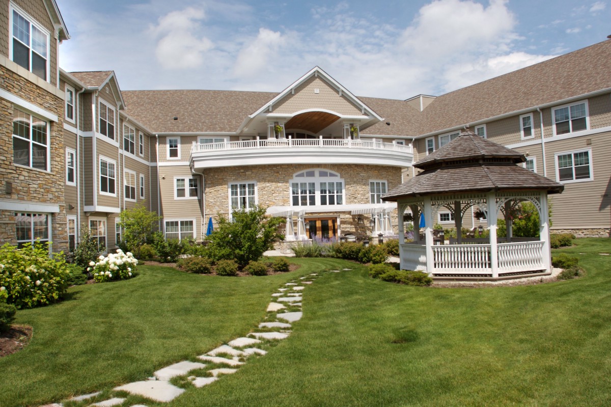 A large building with a well-maintained garden, featuring a stone pathway leading to a gazebo.