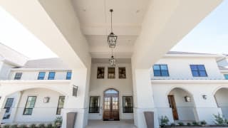 A grand entrance with tall ceilings, featuring elegant hanging lanterns and large windows.