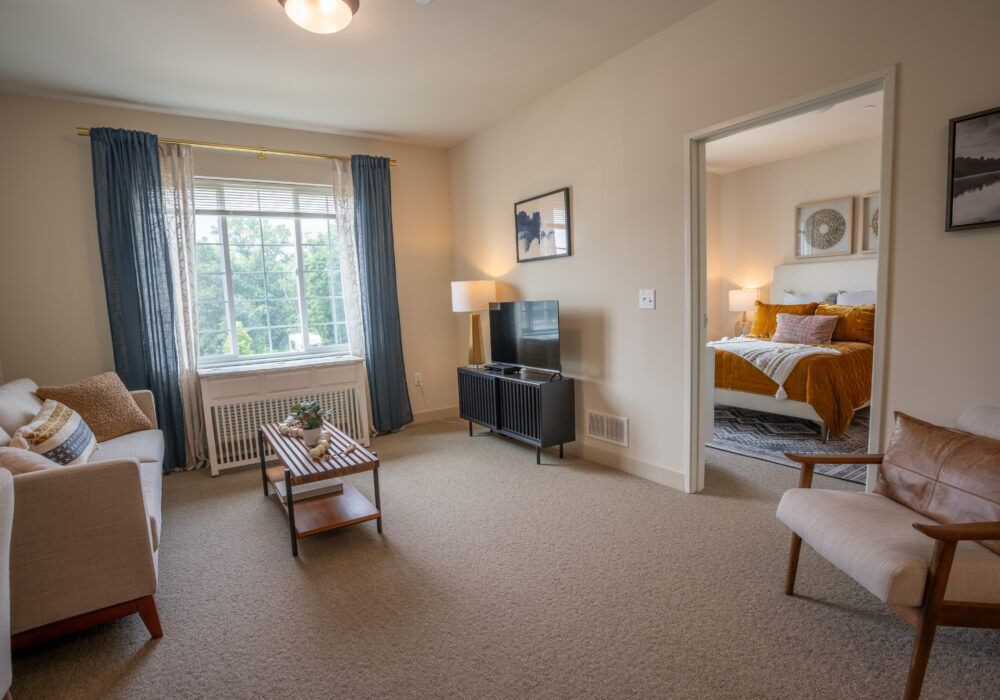 A cozy apartment living room with a view into an adjacent bedroom.