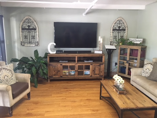 A cozy living room featuring a modern TV setup, wooden furniture, and decorative plants.