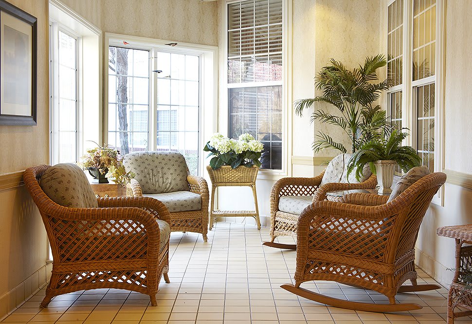 A cozy living room with wicker furniture and indoor plants illuminated by natural sunlight.