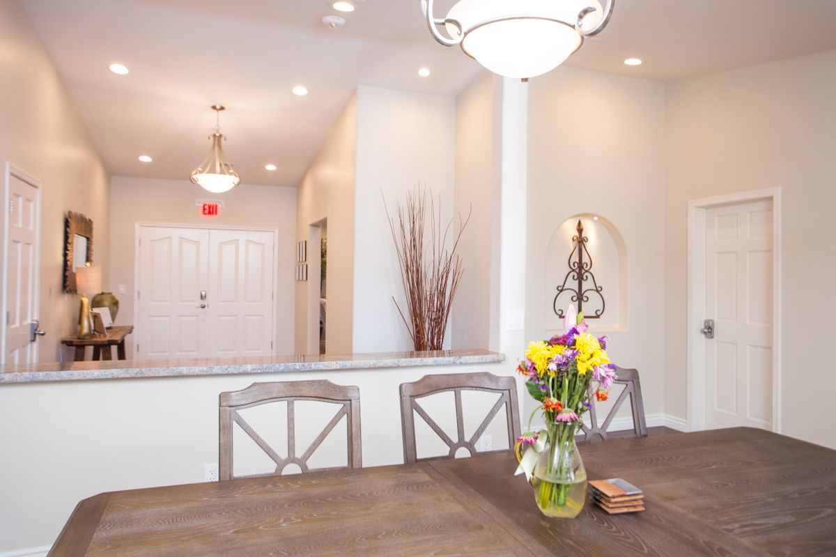 A bright and modern dining room with a table, chairs, and a vase of flowers.