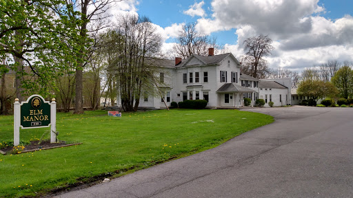 A charming white house surrounded by greenery and a blue sky.