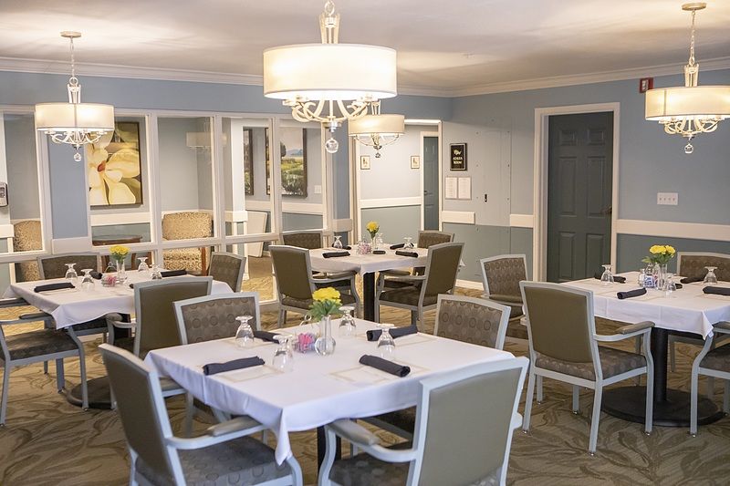 An elegant dining room featuring neatly arranged tables and chairs under a stylish chandelier.