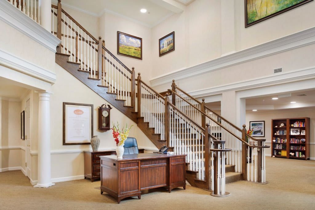 A welcoming interior featuring a grand staircase and a reception desk adorned with artwork.