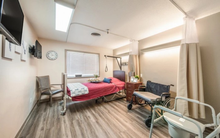 An empty hospital room featuring a patient bed and wheelchair.