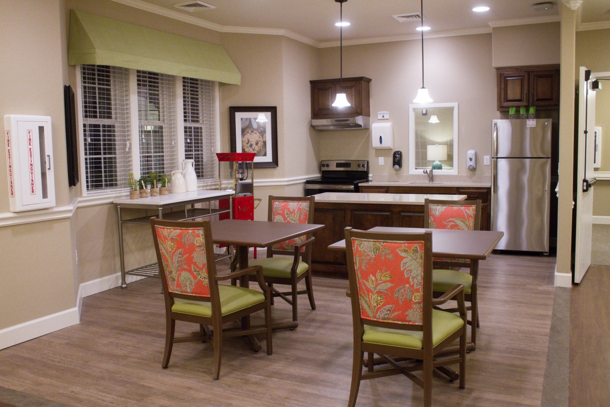 A cozy kitchen and dining area with wooden furniture, floral chair upholstery, and modern lighting fixtures.