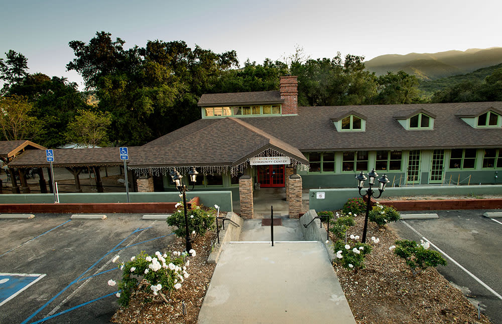 An elegant restaurant building with a landscaped pathway and flowers leading to the entrance.
