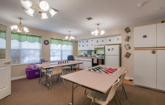 A classroom setup with tables, chairs, and a kitchen area.