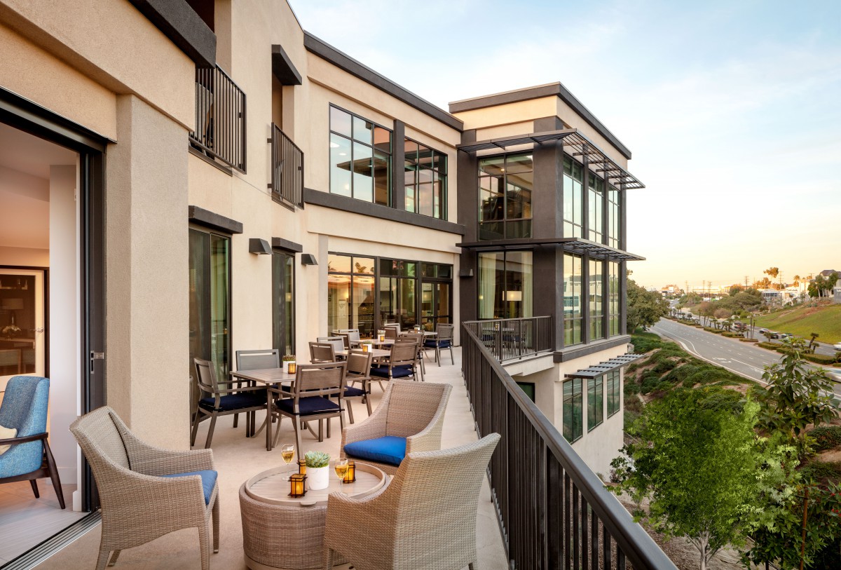 A modern building with a spacious balcony featuring stylish patio seating.