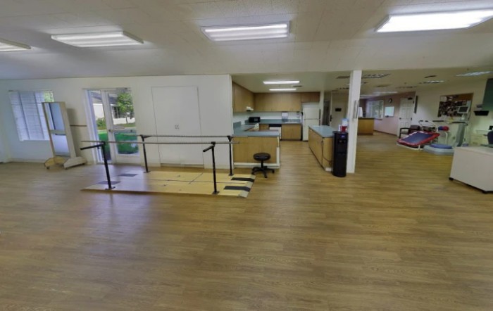 A spacious rehabilitation center with wooden flooring and exercise equipment.