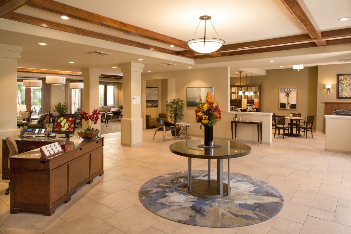 A modern and elegantly designed lobby area with stylish furniture, warm lighting, and decorative floral arrangements.