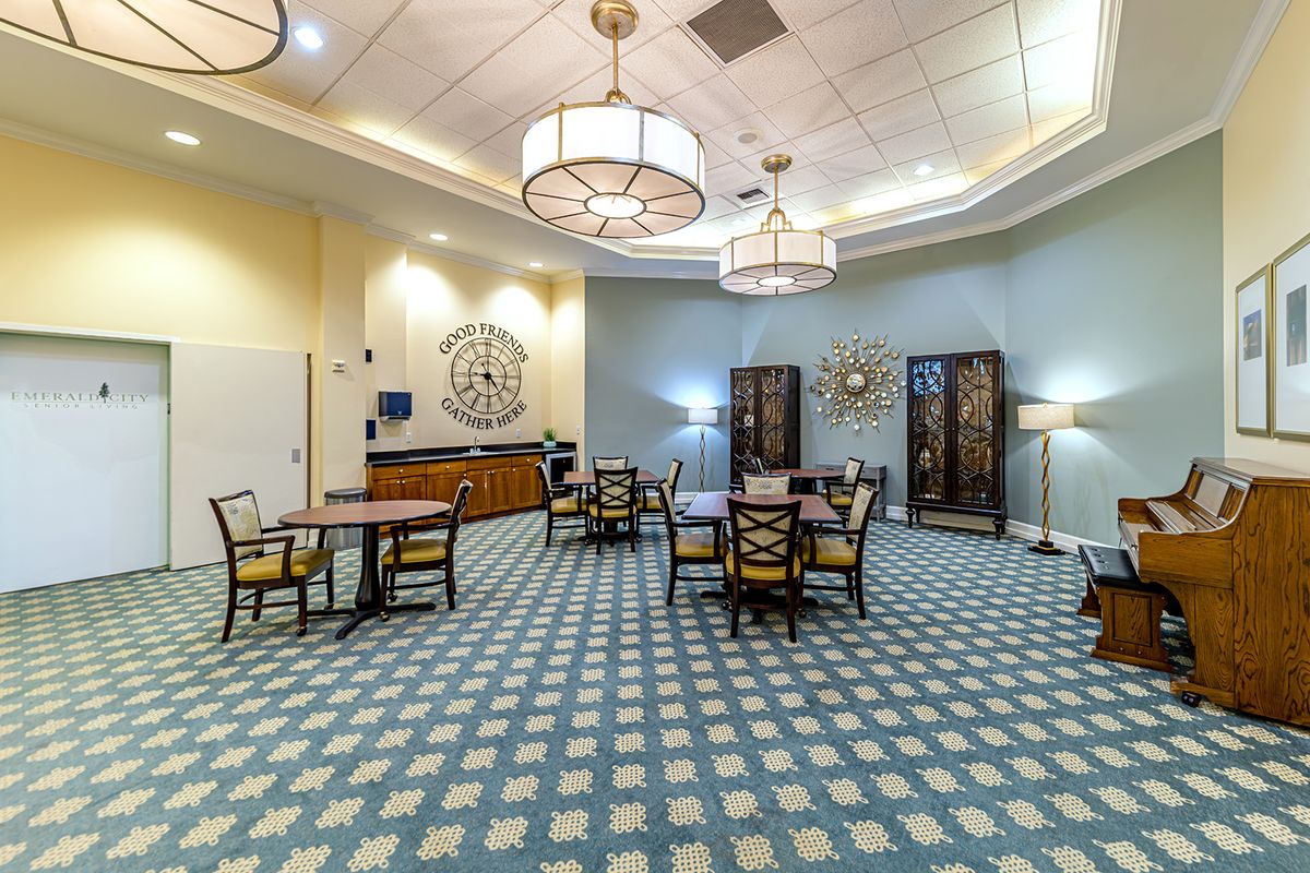 A well-lit dining area with tables and chairs, featuring decorative panels and hanging lights.