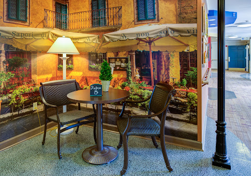 A cozy seating area featuring a small table and two chairs, complemented by a warm ambiance from the lamp and a picturesque mural.