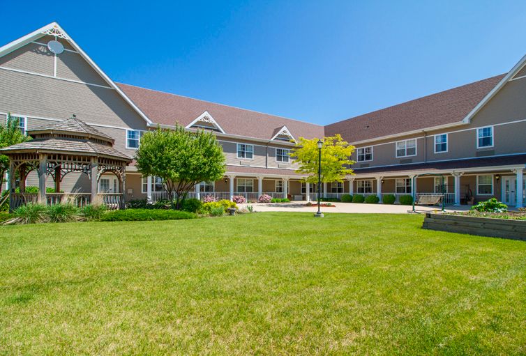 A large residential building with a well-maintained lawn and garden area under a clear blue sky.