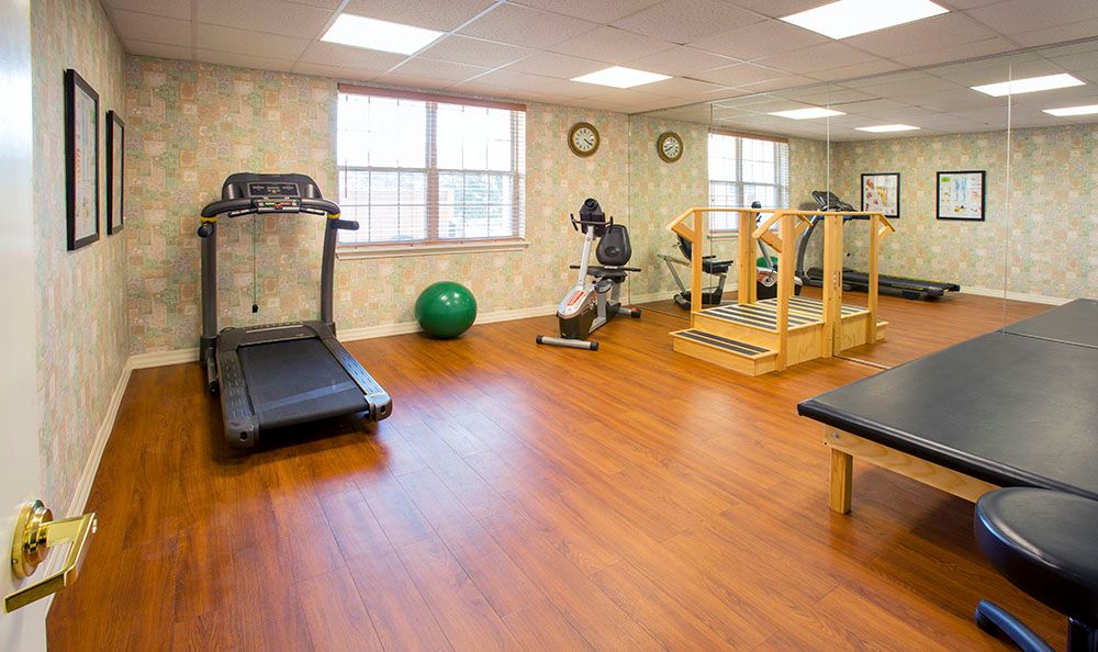 A small gym with exercise equipment including a treadmill and yoga ball.