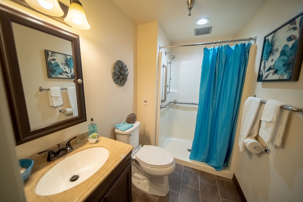 A clean and modern bathroom with a sink, toilet, and blue shower curtain.