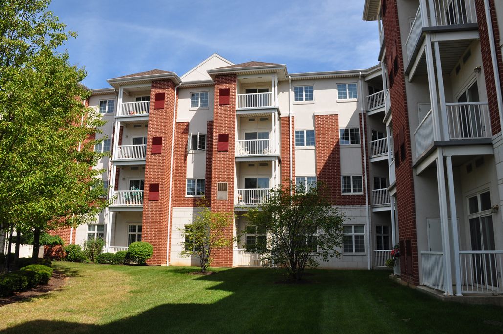 A residential apartment building with brick and white facade under a clear blue sky.