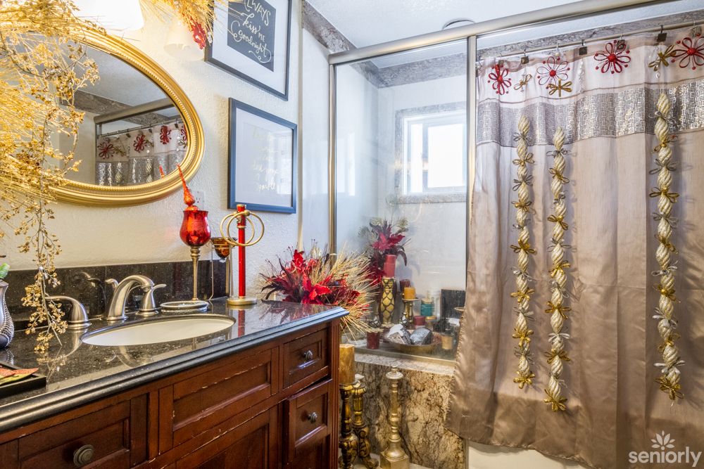 A well-decorated bathroom with a mirror, vanity, and shower area adorned with flowers.