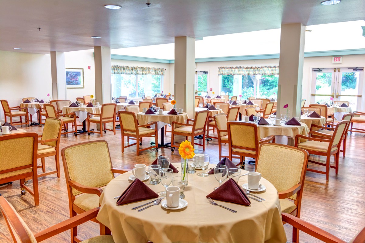 An elegant dining room with neatly arranged tables and chairs, set for a meal.