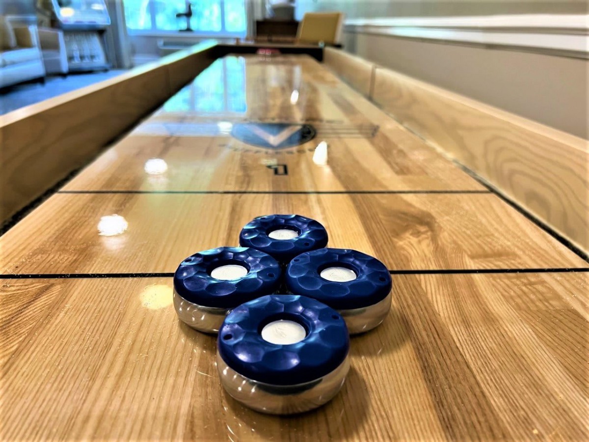 Four blue shuffleboard pucks neatly arranged on a wooden table.