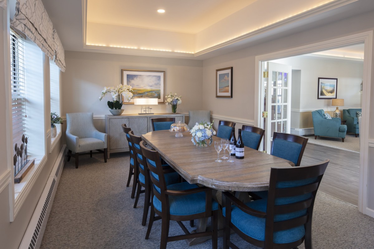 A well-decorated dining room featuring a long table with blue-cushioned chairs, soft lighting, and elegant decor.