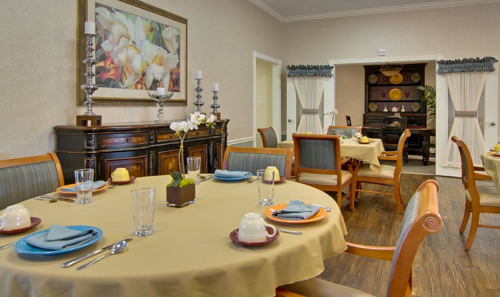 A cozy dining room with tables set for a meal, featuring elegant decor and warm lighting.