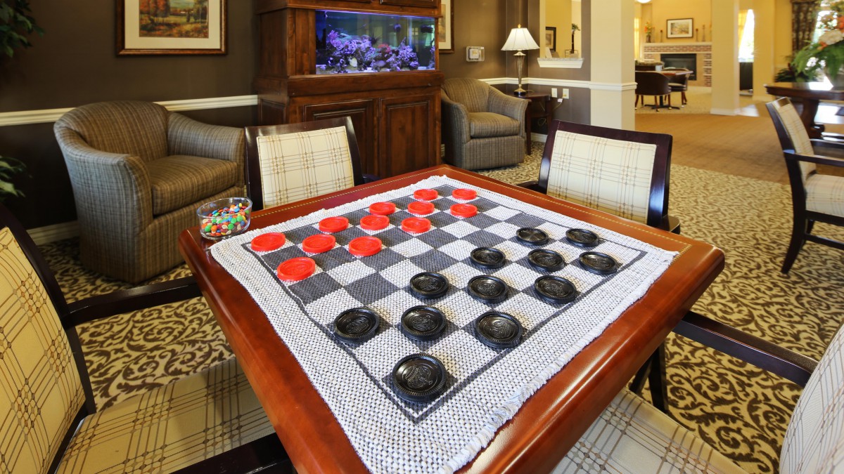 A checkers board setup with red and black pieces on a table.