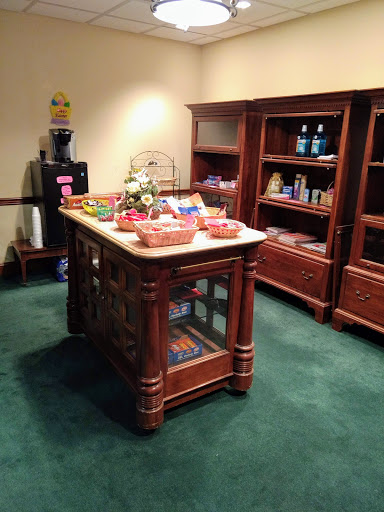 A cozy setup featuring a wooden display island filled with snacks and surrounded by shelves in a reception area.