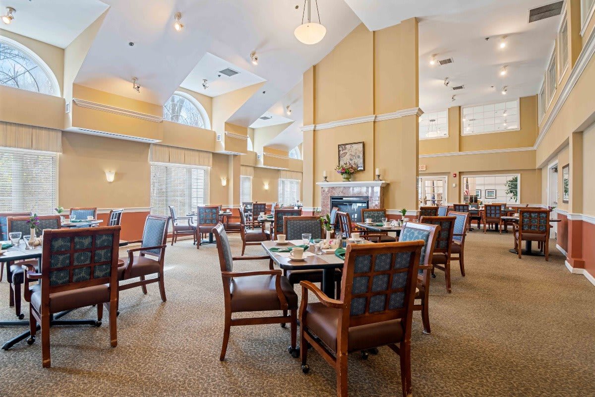 A spacious and well-lit dining area with tables and chairs arranged neatly, featuring warm decor.