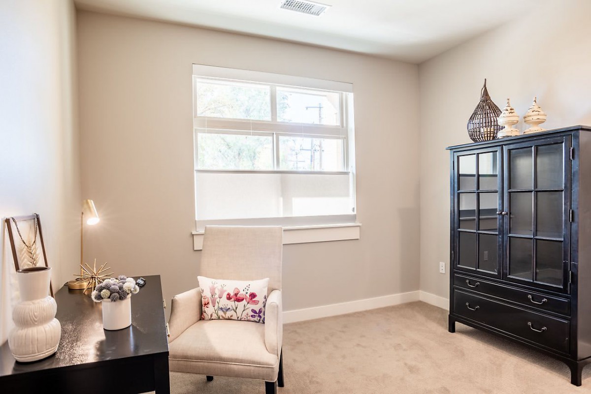 A bright and cozy home office with a desk, chair, and decorative elements.
