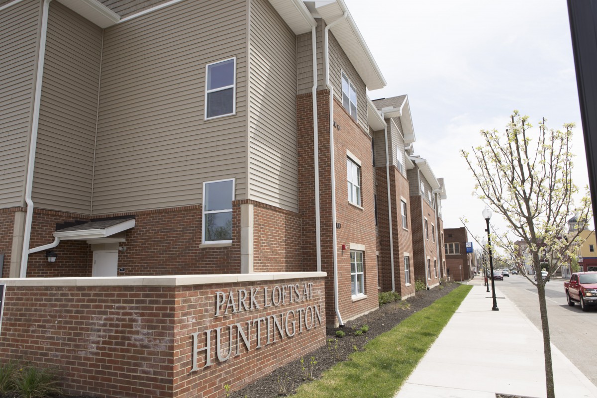 A modern apartment building with a brick exterior and multiple floors, located in an urban setting.