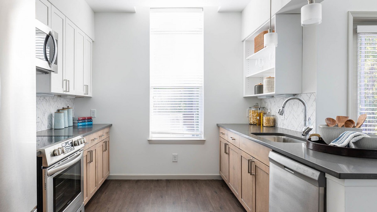 A bright and modern kitchen with light wood cabinets and a large window.
