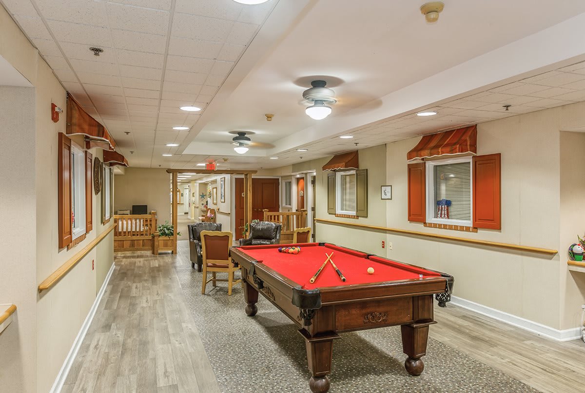 A cozy game room featuring a red pool table and comfortable seating.