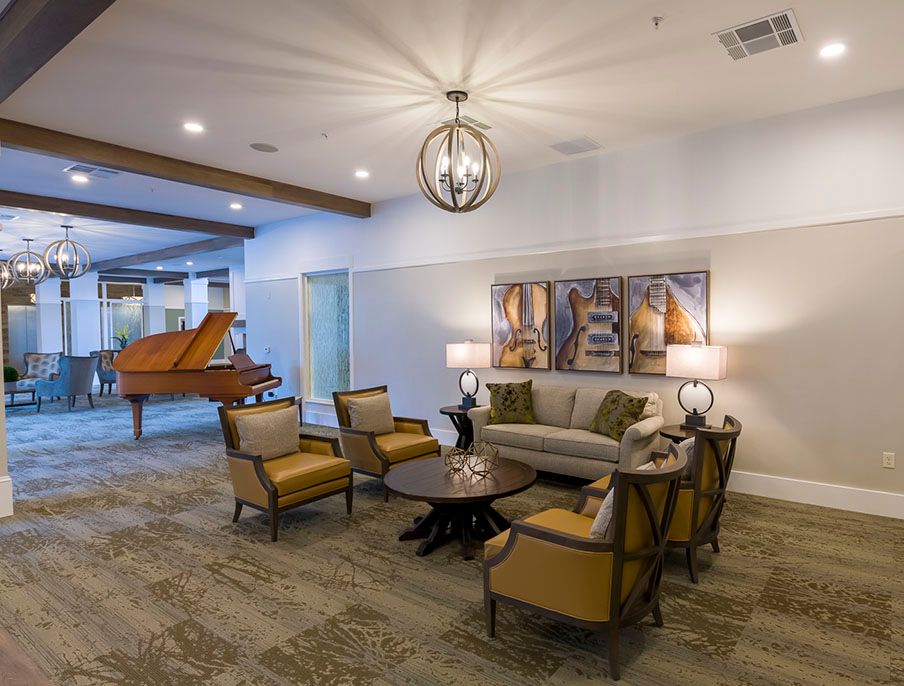 A well-furnished living room with elegant seating and a piano in the background.