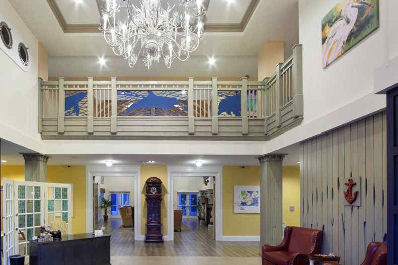 A well-lit lobby featuring a chandelier, balcony, and a grandfather clock.