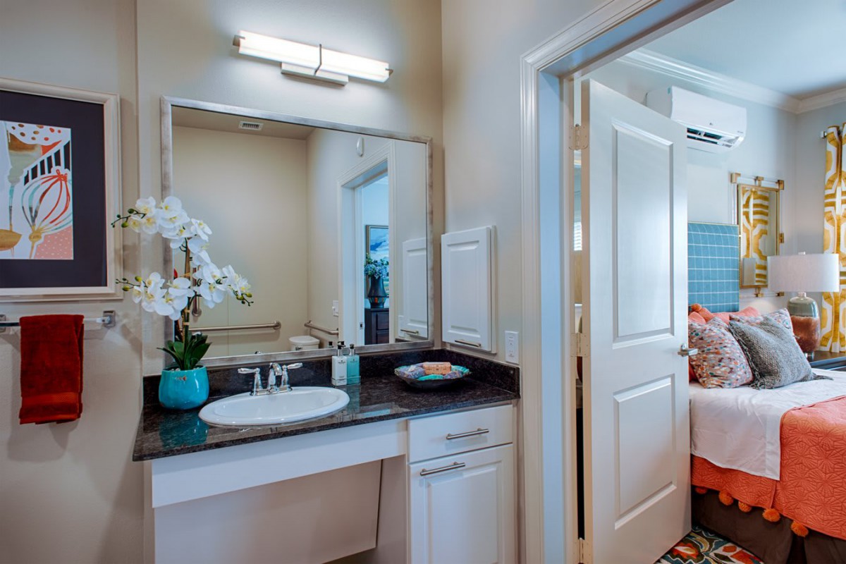 A well-lit bathroom interior featuring a sink with decorative flowers and a large mirror.