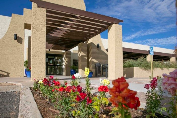 Beautiful entrance with a flower bed and pergola on a sunny day.