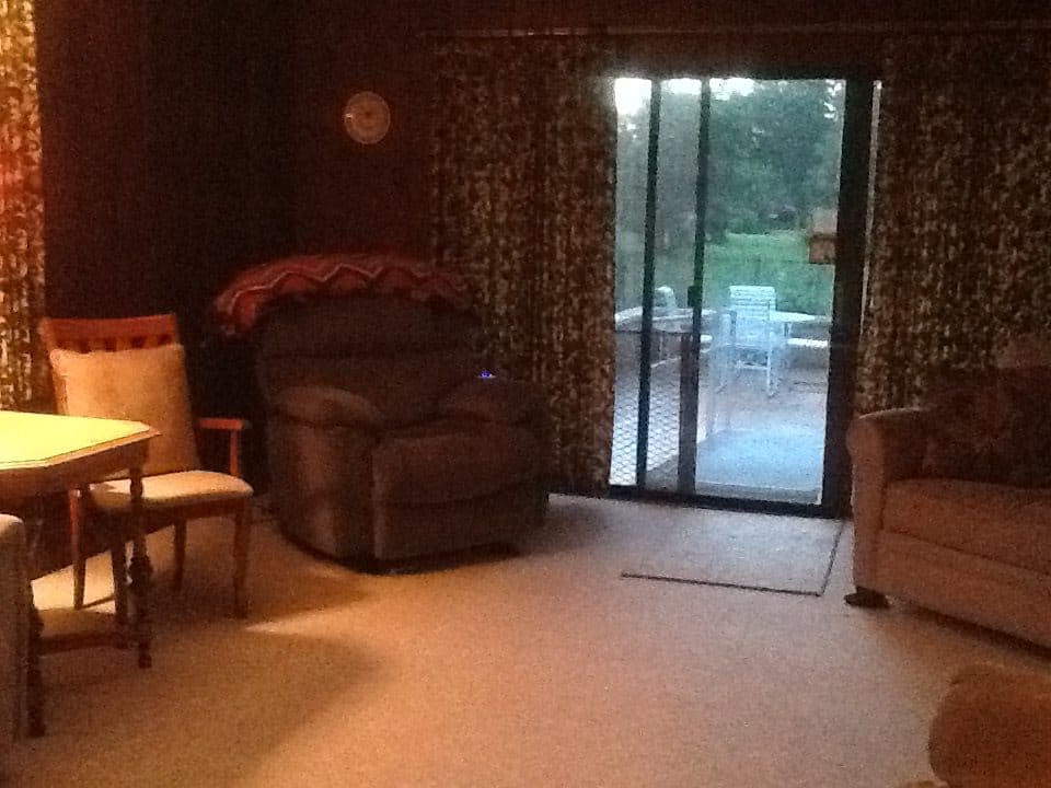 A cozy living room with an armchair and sliding glass doors leading to a patio.
