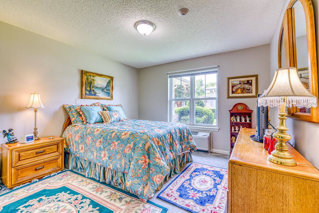 A cozy bedroom with floral bedding and colorful decor.