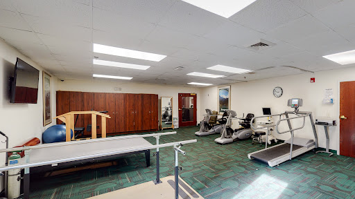 A bright and spacious rehabilitation gym equipped with various exercise machines and physical therapy tools.
