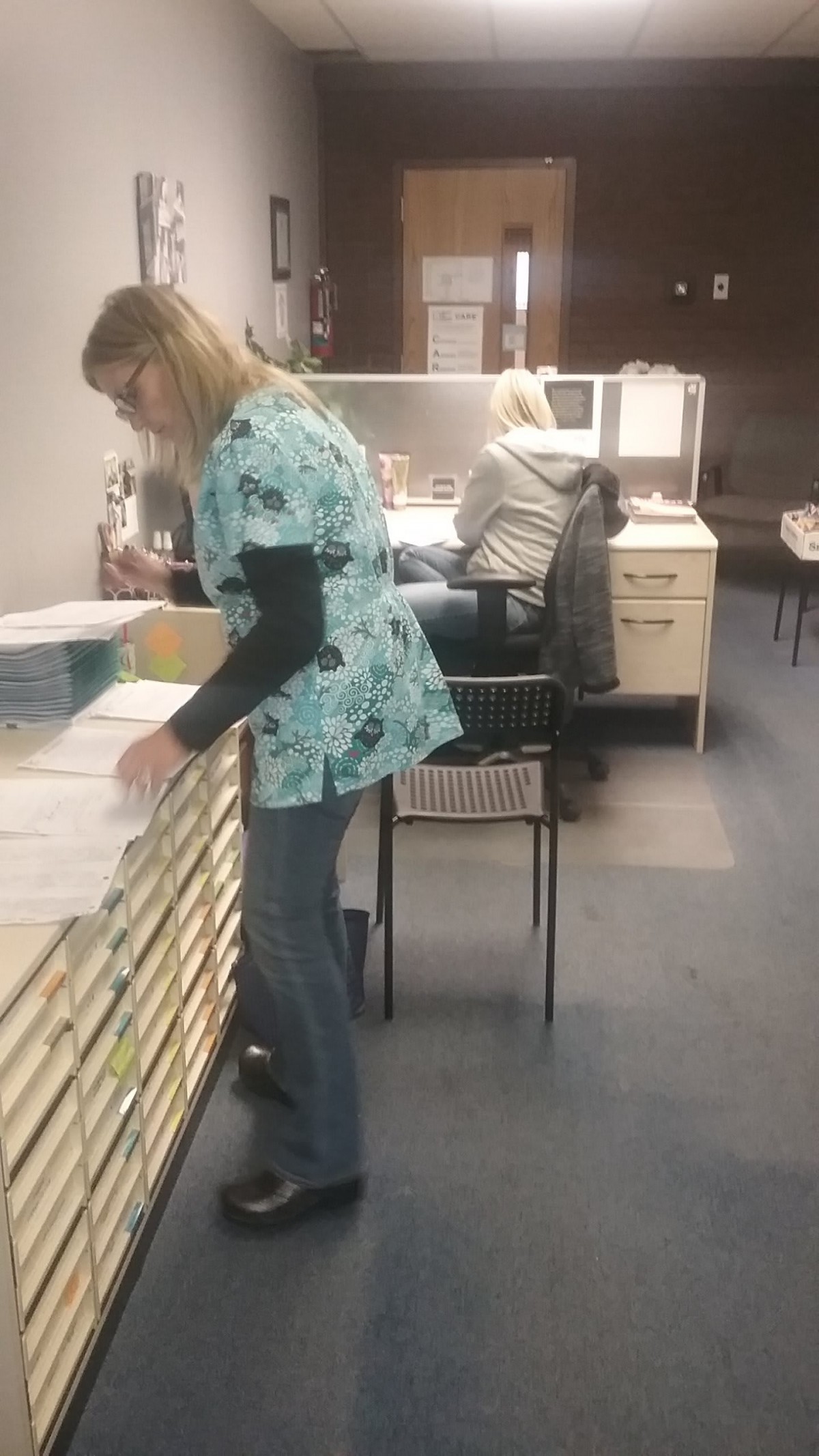 Two women working in an office, organizing files and paperwork.